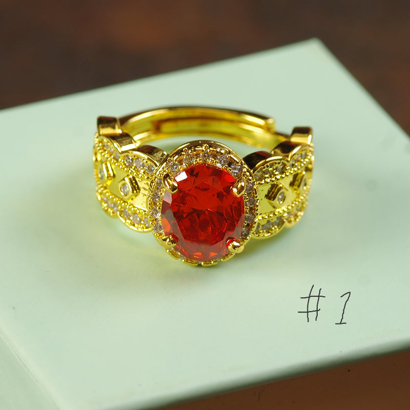 Gold ring with a red gemstone on a light green surface